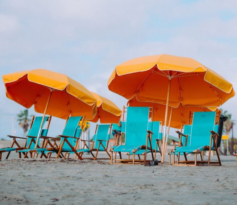 Orange Umbrella and blue chairs on beach